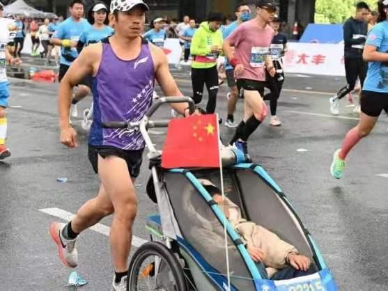 父亲推着脑瘫儿子跑完55场马拉松： 爸爸推着轮椅跑马拉松