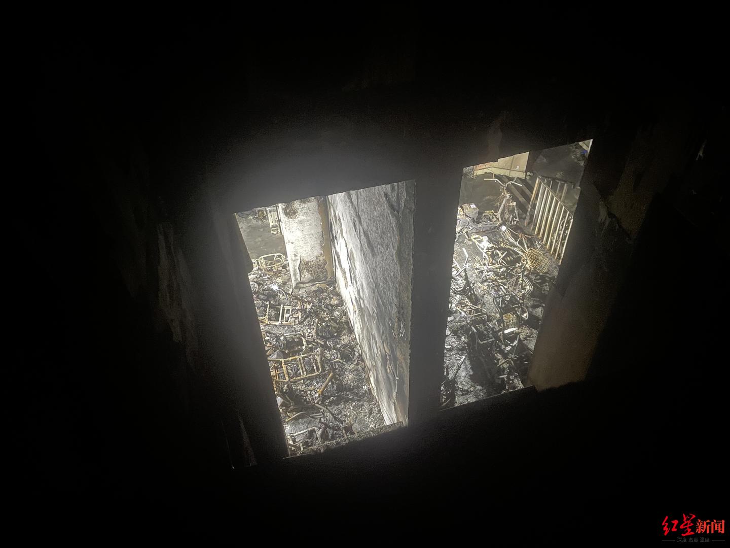 南京火灾楼栋内景：天井连通1楼架空层，可见大量电动车残骸，空调外机扇叶消失
